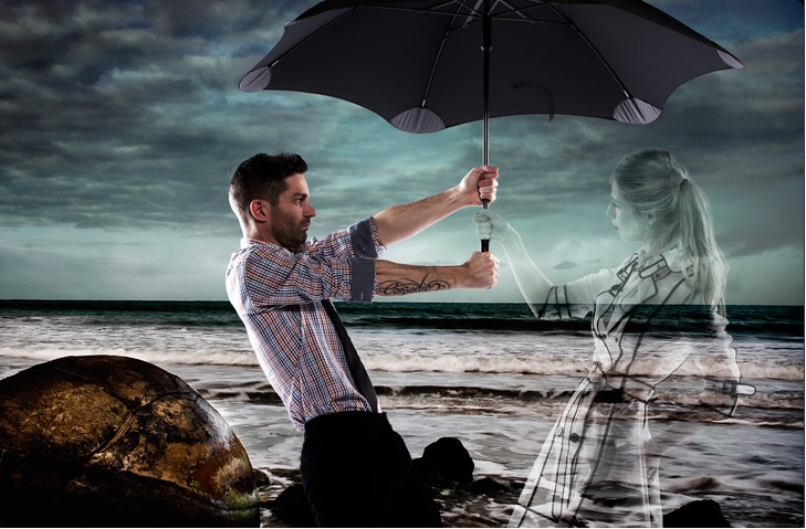 Мужчина держит зонт над женщиной